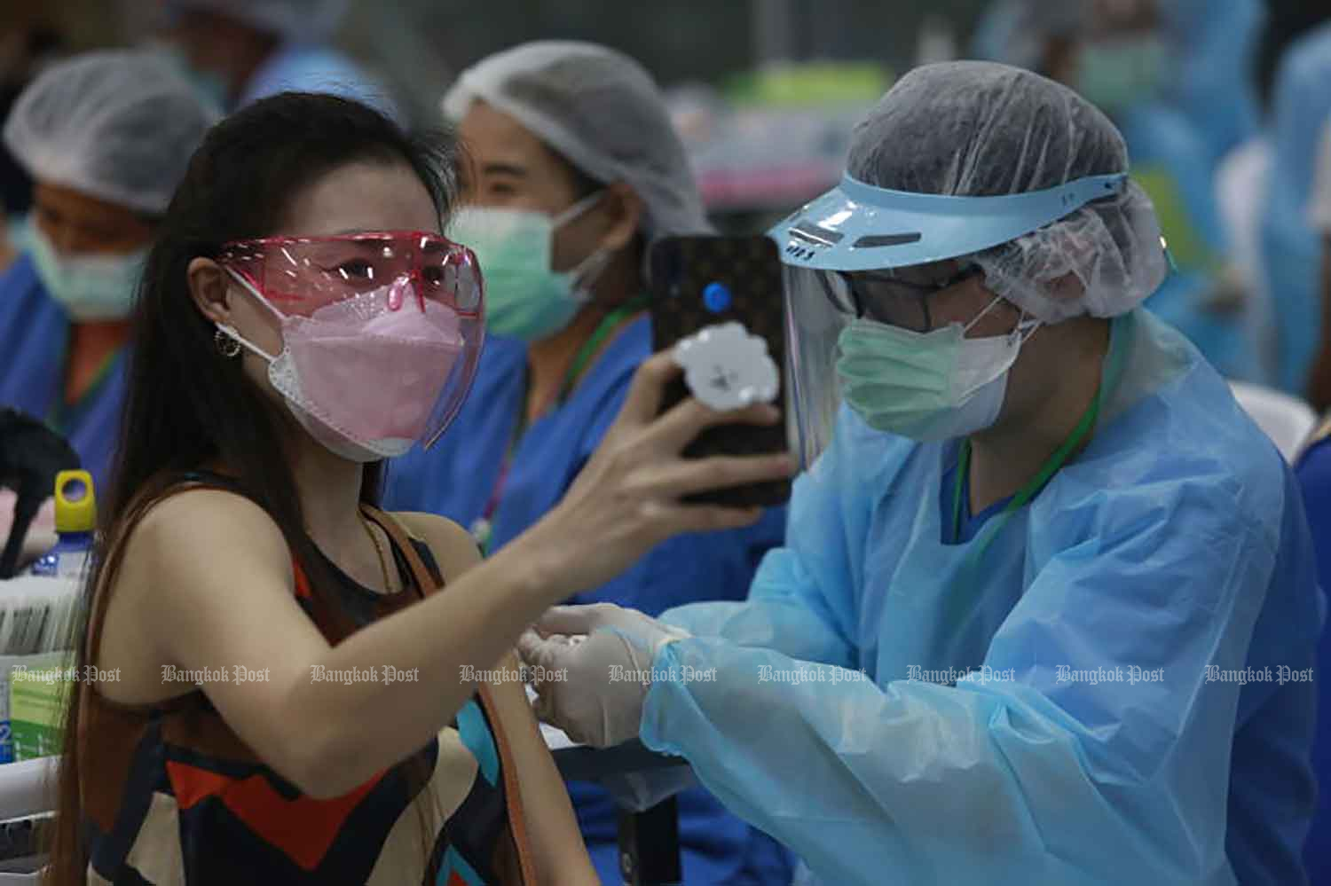 A woman takes a selfie while being inoculated with Covid-19 vaccine at Bang Sue Grand Station in Chatuchak district, Bangkok, on June 7, 2021. (Photo by Arnun Mahachontrakool)