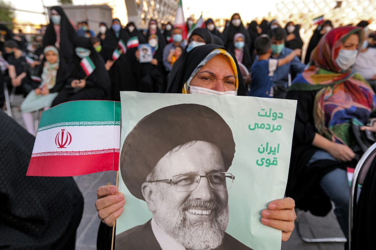 A woman holds a poster of Iran's newly-elected president Ebrahim Raisi, with text in Persian reading "government of the people, strong Iran", as supporters celebrate his victory in Imam Hussein square in the capital Tehran on Saturday.