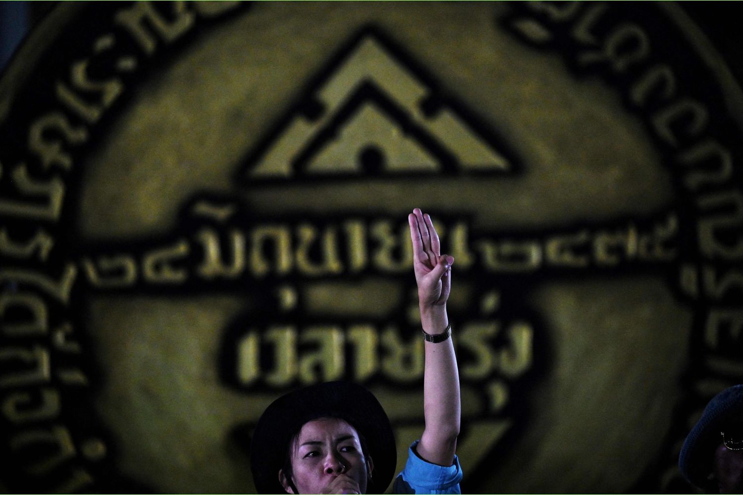 A pro-democracy activist stands in front of a large replica of the 1932 Siamese Revolution plaque as they gather to commemorate the 89th anniversary of the end of absolute monarchy at Democracy Monument in Bangkok on Thursday. (AFP photo)