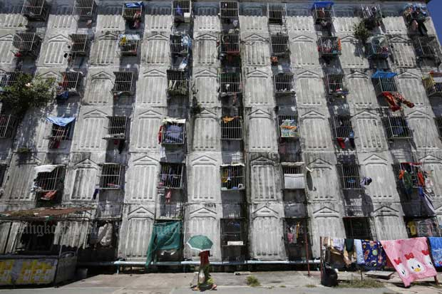 A woman walks past a migrant worker dormitory in Bang Phli district in Samut Prakan on Sunday. (Photo: Wichan Charoenkiatpakul)