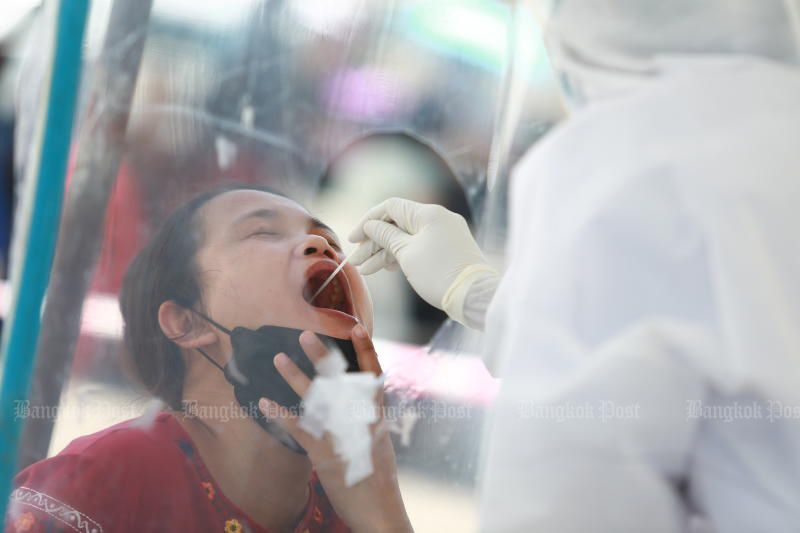 A health official takes a swab from a woman, for testing for Covid-19, at a health centre in Pathumwan district of Bangkok on Thursday. The capital has by far the largest number of new cases and deaths in the third Covid-19 wave. (Photo: Somchai Poomlard)