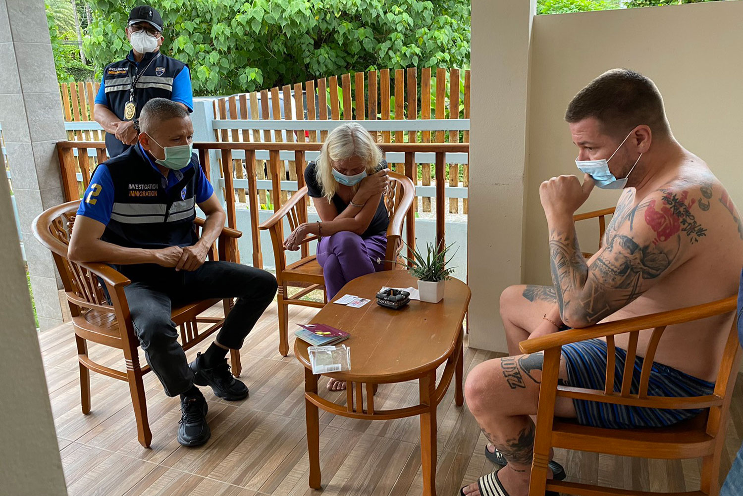 An immigration police officer interrogates one of two German drugs fugitives arrested on Tuesday morning. (Immigration Bureau photo)