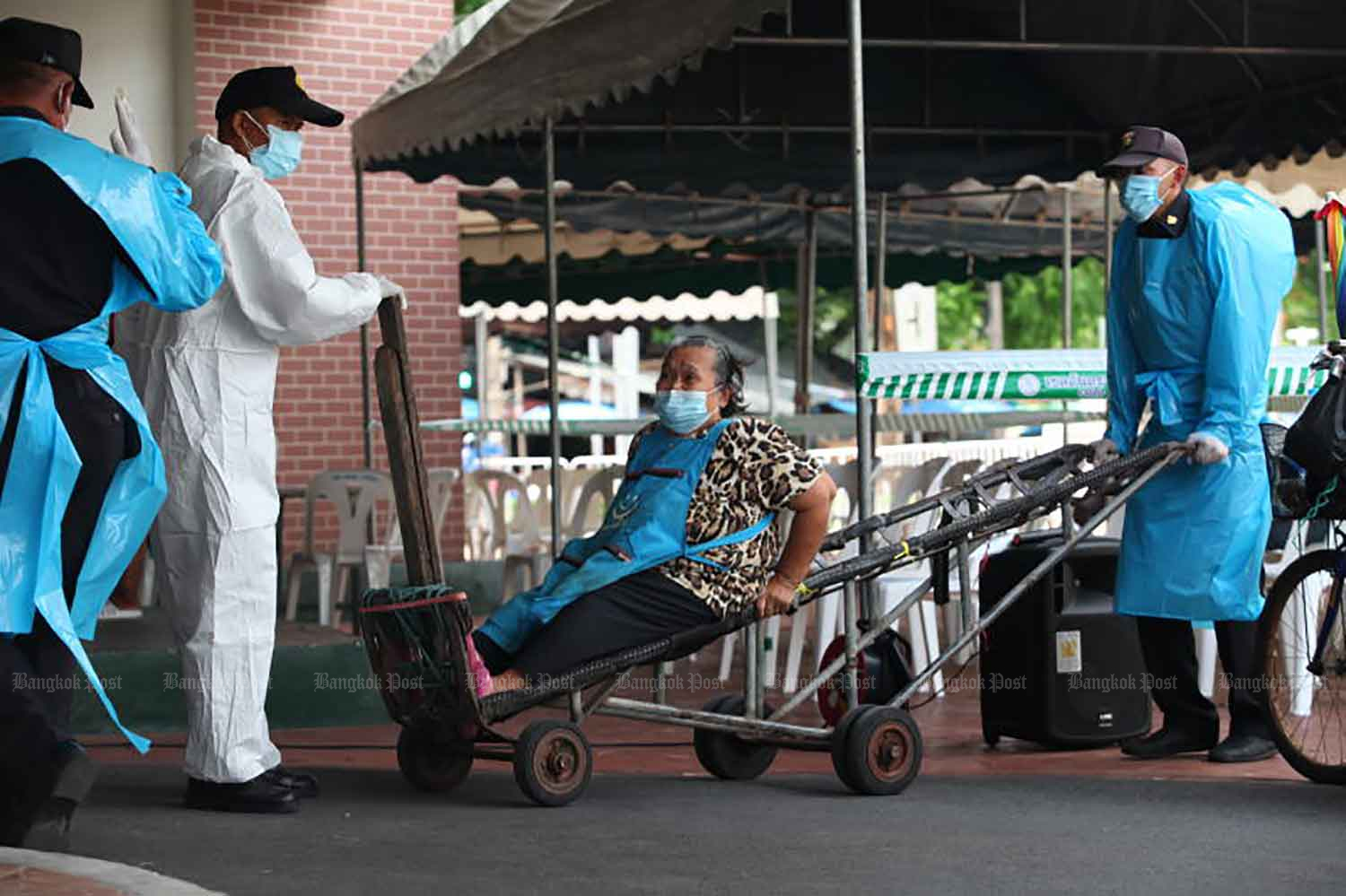 Medical workers use a handcart to move an elderly woman to a Covid testing site located in Mahanak fresh market in Bangkok's Dusit district on Friday. (Photo: Apichart Jinakul)