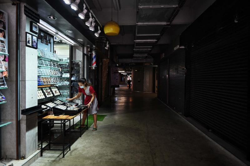 A jewellery vendor arranges wares at a stall surrounded by empty shops in Siam Square on Sunday. (AFP photo)