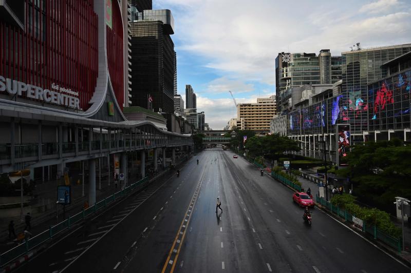 A man crosses the road on Ratchaprasong intersection in Bangkok on Monday, the first day of stricter lockdown restrictions to try to contain the spread of the Covid-19 coronavirus. (AFP photo)