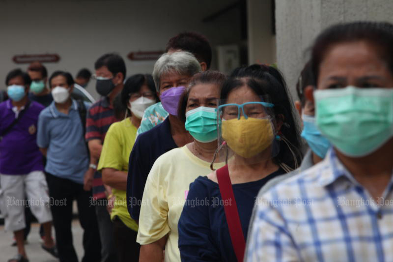 People flock to Siriraj Hospital on Friday for a free Sinopharm vaccine dose, donated by the Chulabhorn Royal Academy. The deteriorating Covid-19 situation was cited by Syn Mun Kong Insurance in terminating its clients' coronavirus insurance policies. (Photo: Apichart Jinakul)