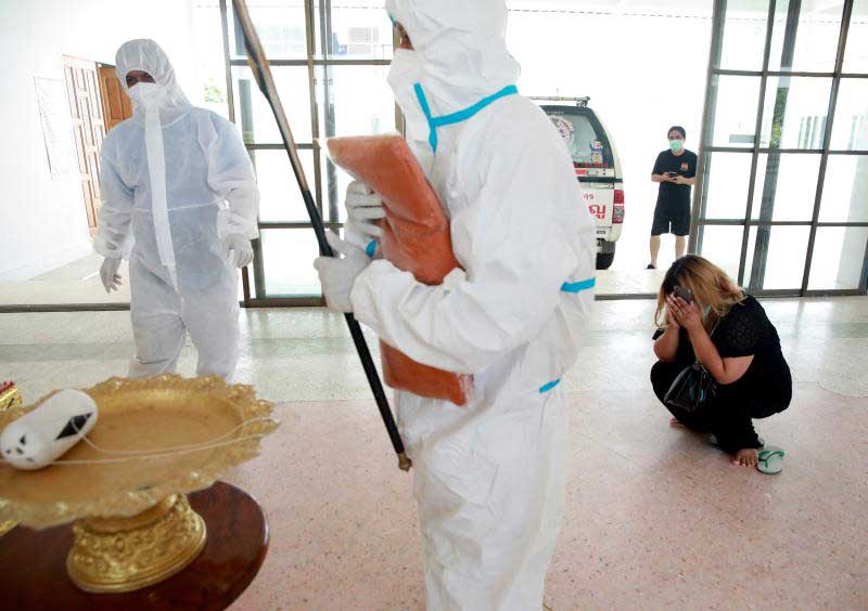 A family member weeps as monk Pongpetch Santijittho wears a protective suit over his robe to cremate the body of a coronavirus victim at Wat Chin Wararam Worawihan in Muang district of Pathum Thani on Thursday. (Reuters photo)