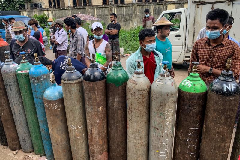 This picture taken on July 14, 2021 shows people waiting to fill up empty oxygen canisters outside a factory in Yangon, amid a surge in the number of Covid-19 coronavirus cases. (AFP)