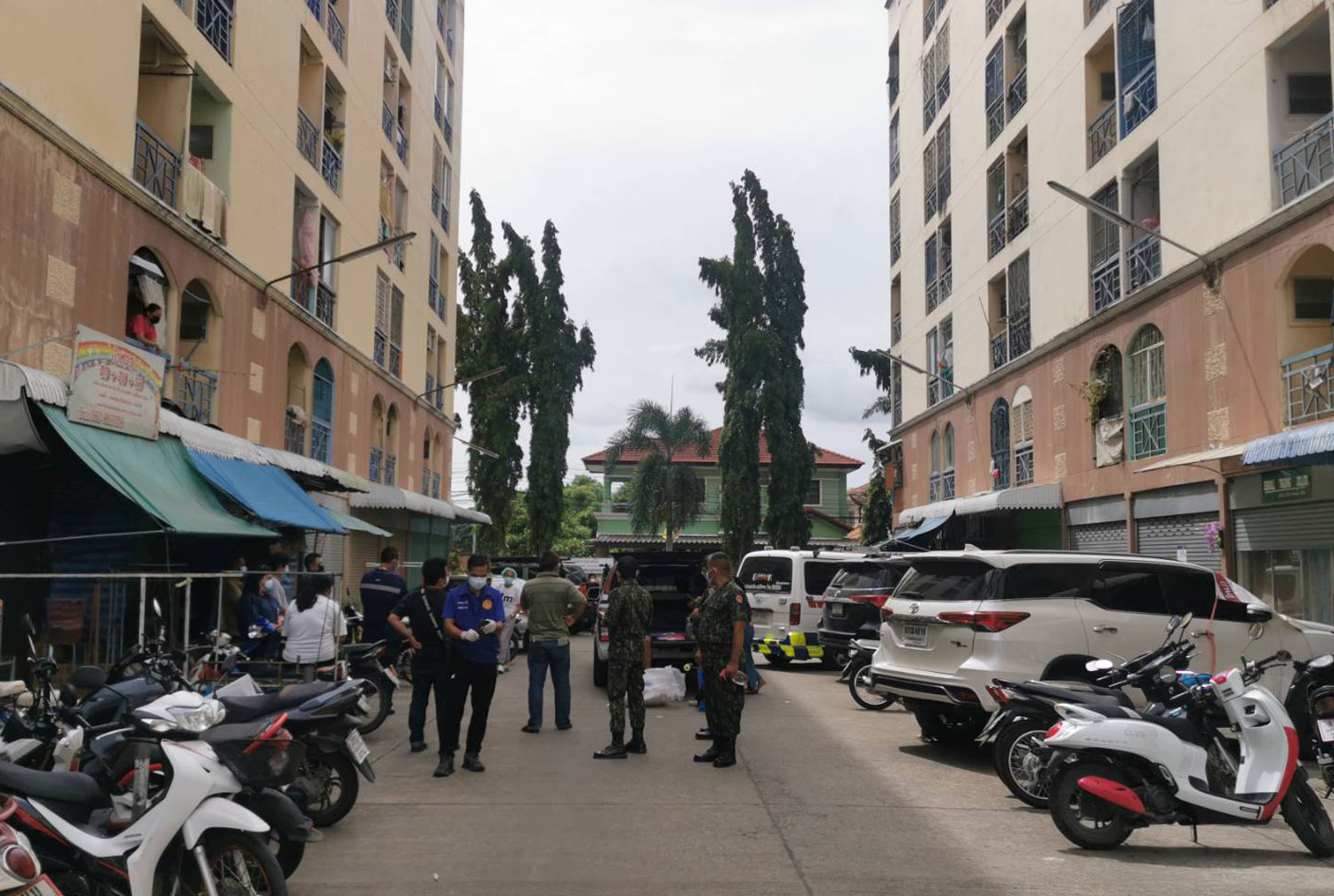 Officials gather at the condo building where an elderly Covid-infected security guard waiting for a hospital bed hanged himself on Thursday morning, in Bang Bua Thong district of Nonthaburi province. (Photo supplied via Wassayos Ngamkham)