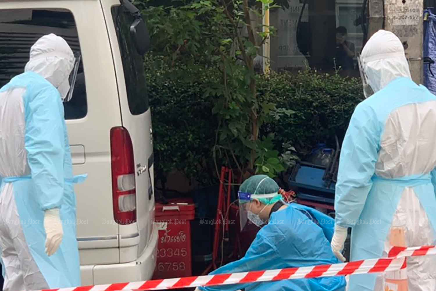 Medical workers in protective suits examine the body of a man found dead on Soi Sukhumvit 20 in Watthana district, Bangkok, on Thursday morning. (Photo supplied)