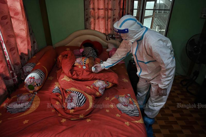 A volunteer from the Zendai organisation checks the blood oxygen level of a woman in home isolation in a Covid-19 stricken community in Nong Chok district in Bangkok on Monday. (AFP photo)