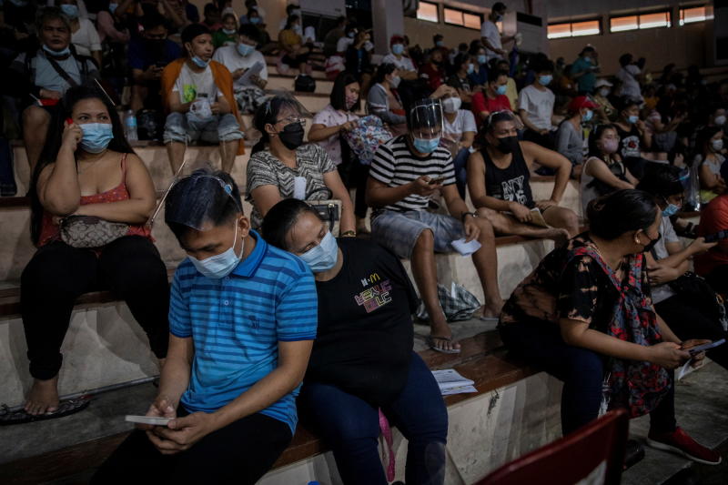 A woman takes rest while queueing for free vaccination against the coronavirus disease at San Andres Sports Complex in Manila on July 21, 2021. (Reuters photo)