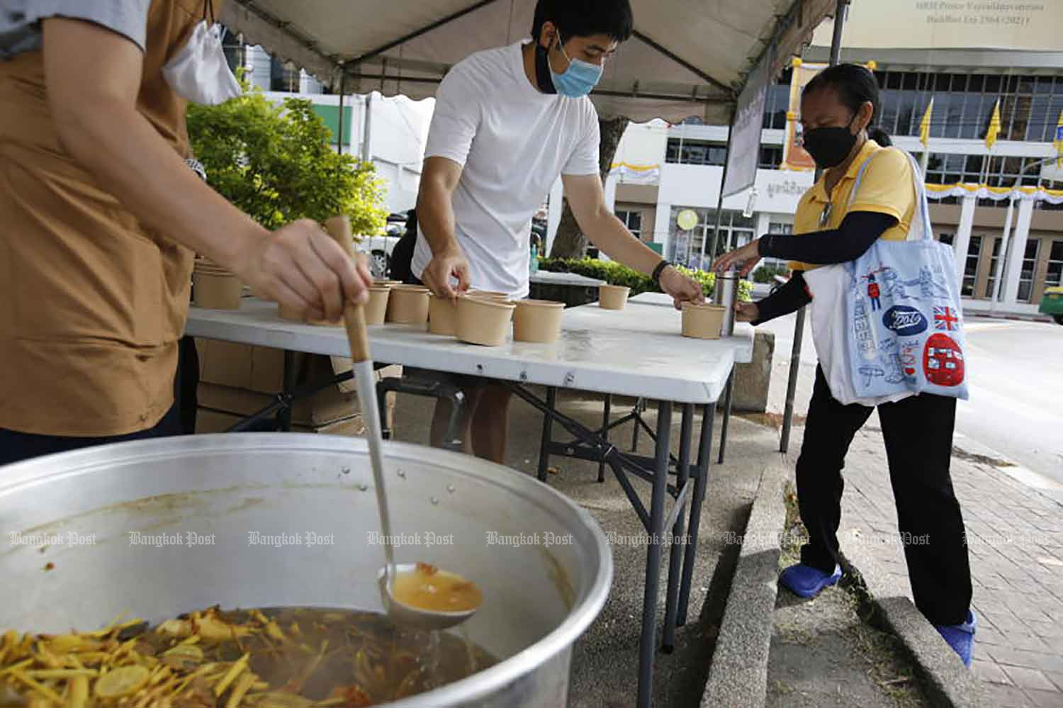 People from the Team Dharma Thurakij group offfer a free drink in Bangkok on Monday. The herbs mixed in the drink, including fingerroot, are believed to help ward off Covid-19. (Photo: Wichan Charoenkiatpakul)