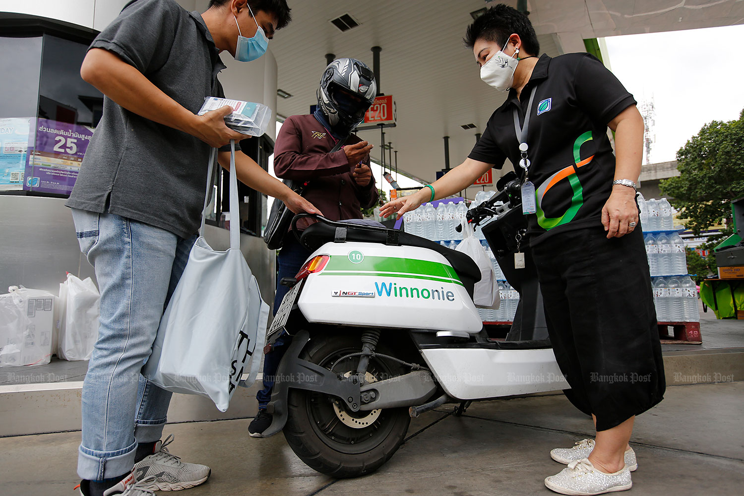 Herbal aid: A pump attendant at a petrol station in Bang Chak hands off packets of ‘fah talai jone’ to a courier who will deliver the herbal medicine free of charge to Covid-19 sufferers being treated at home. (Photo: Wichan charoenkiatPakul)