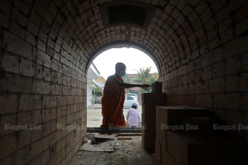 A monk works on a new furnace in the crematorium at Wat Chinwararam in Pathum Thani’s Muang district on July 26, 2021. The temple is building six new furnaces to accommodate the increasing demand for cremations amid the pandemic. (Photo: Chanat Katanyu)