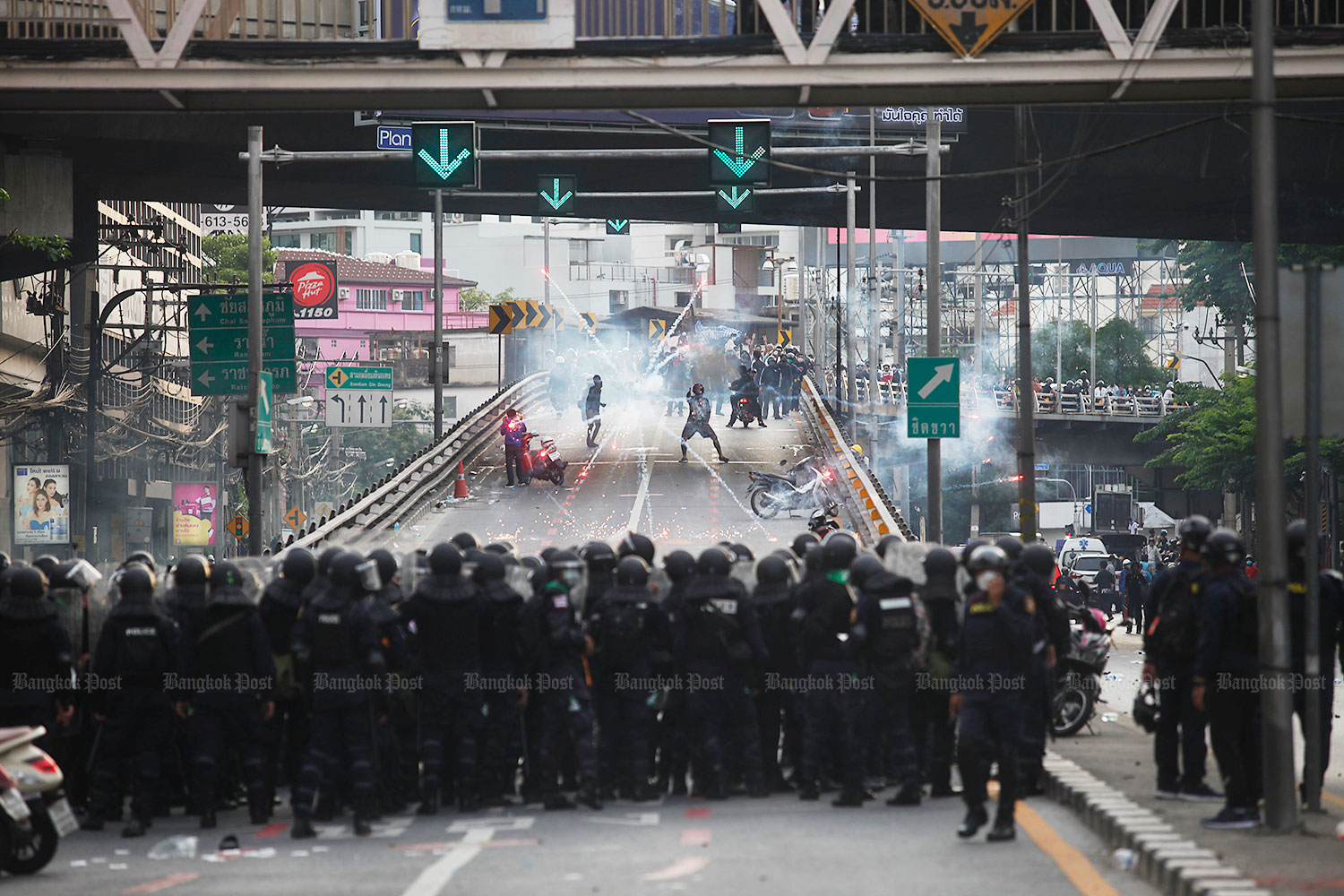 Policemen stand their ground in a tense confrontation with protesters at the flyover near Victory Monument late Tuesday afternoon. (Photo: Nutthawat Wicheanbut)