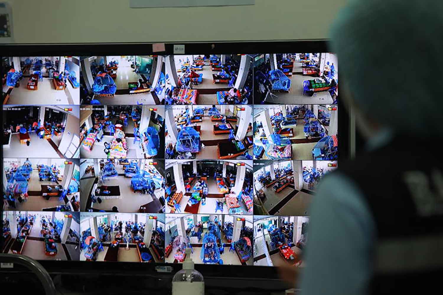 The monitor shows Covid-infected people on Friday rest at a flood response centre which the Bangkok Metropolitan Administration turned into an isolation facility in Prawet district. (Photo: Apichart Jinakul)