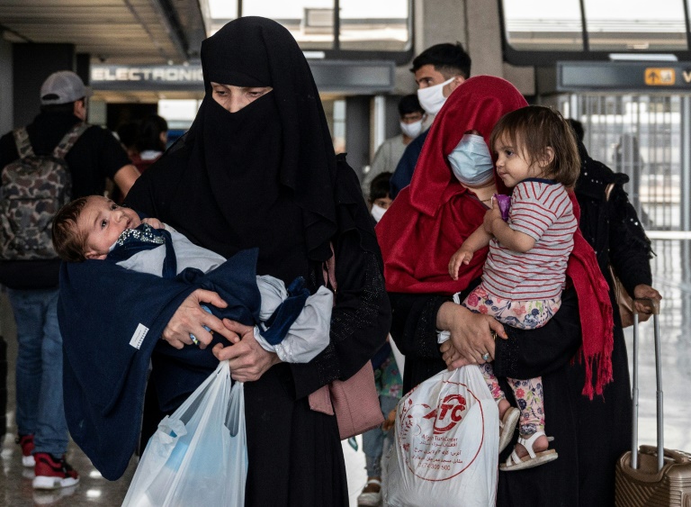 Refugees from Afghanistan are escorted to a waiting bus after arriving at Dulles International Airport in Dulles, Virginia. Refugees from Afghanistan are escorted to a waiting bus after arriving at Dulles International Airport in Dulles, Virginia.