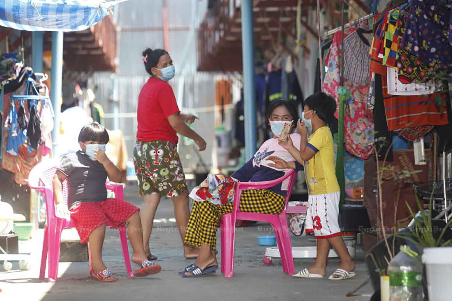 A family relaxes inside a construction-site camp on Soi Phahon Yothin 15 in Bangkok on Tuesday. The camp was the centre of a Covid-19 cluster but is now virus-free and the residents are back at work. (Photo: Nutthawat Wicheanbut)