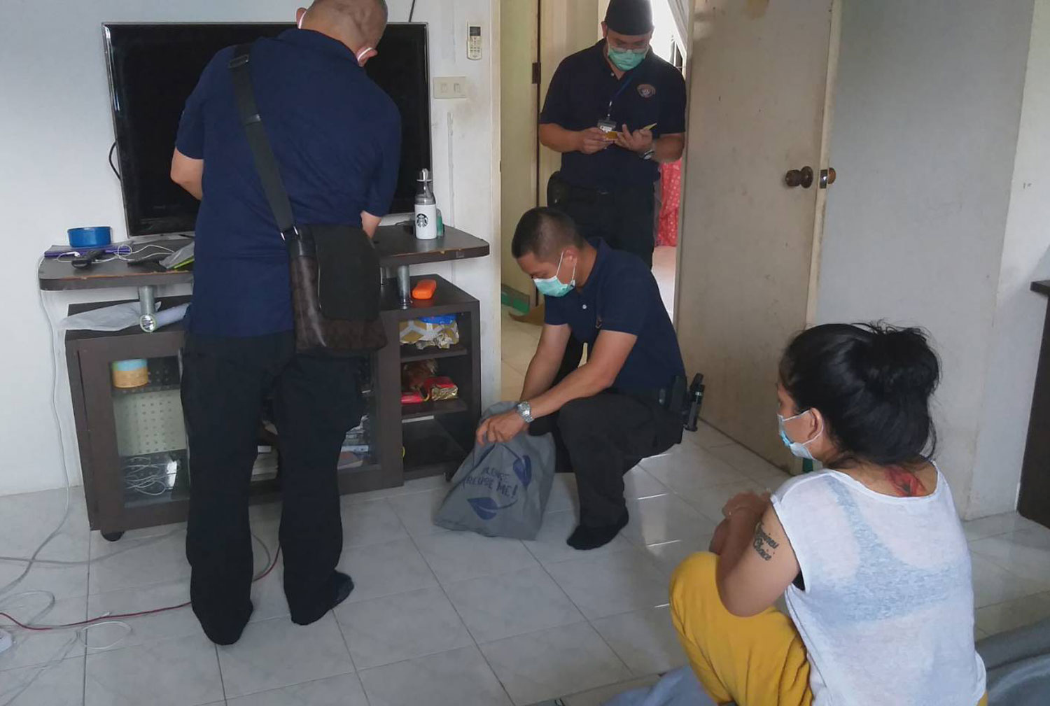 Wanwisa Pilatan, 24, watches as police search her room in Bangkok's Ratchathewi district on Tuesday. She and her Nigerian husband were charged with attempting to smuggle 9kg of crystal methamphetamine to Hong Kong hidden in a shipment of shoulder bags. (Photo: Crime Suppression Division) Wanwisa Pilatan, 24, watches as police search her room in Bangkok's Ratchathewi district on Tuesday. She and her Nigerian husband were charged with attempting to smuggle 9kg of crystal methamphetamine to Hong Kong hidden in a shipment of shoulder bags. (Photo: Crime Suppression Division)