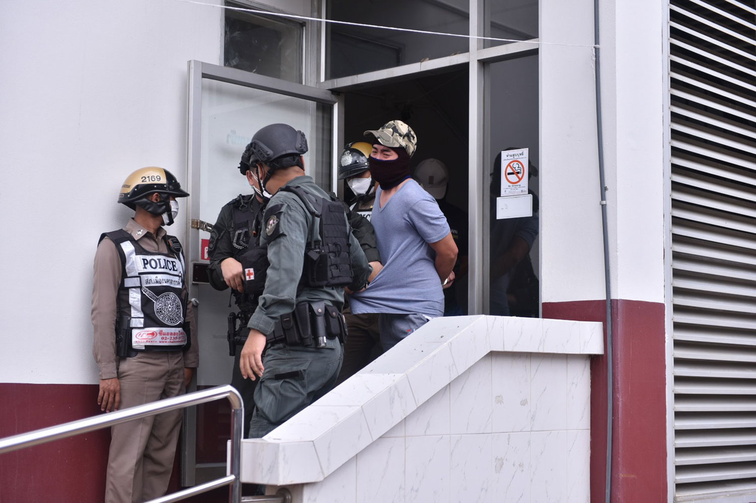 Five of the seven policemen allegedly involved in the fatal torture of a drug suspect are escorted out of Muang police station, heading for Nakhon Sawan Provincial Court on Thursday. (Photo: Chalit Phumruang)