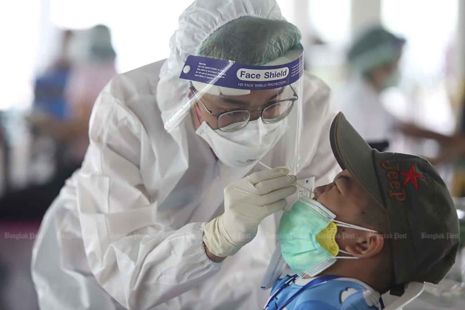 An official of the Bangkok Metropolitan Administration takes a swab for an RT-PCR test for Covid-19 at the Pracha Niwet Sport Centre on Thursday. People who test positive in a rapid antigen test can walk in and request an RT-PCR test. (Photo: Pattarapong Chatpattarawsill)