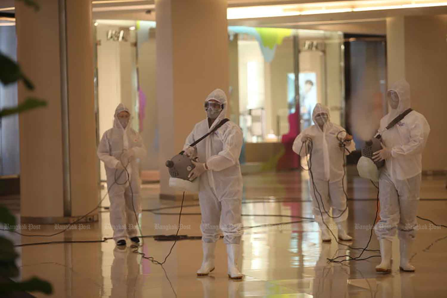 Workers spray disinfectant at a shopping centre in Bangkok on Monday to prepare for reopening on Wednesday. (Photo: Apichart Jinakul)