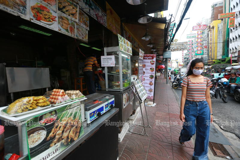 A woman walks past a shop in Yaowarat on Tuesday. (Photo: Somchai Poomlard)