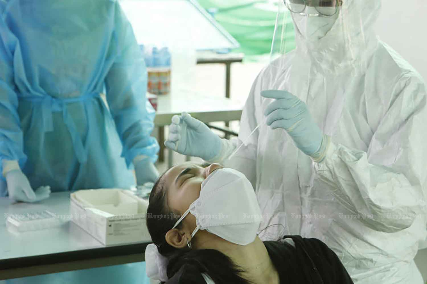 Health workers conduct rapid antigen tests among vendors and workers in Simummuang market in Rangsit, Pathum Thani, on Sunday. The test will be conducted every week to ensure people stay Covid-19 free. (Photo: Apichit Jinakul)