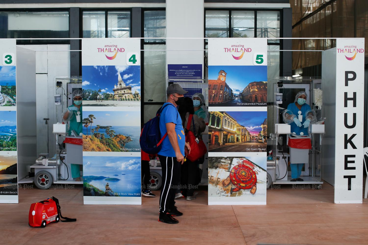 A man stands near health workers at the Phuket airport as the island reopens to vaccinated foreign tourists without quarantine on July 1. REUTERS