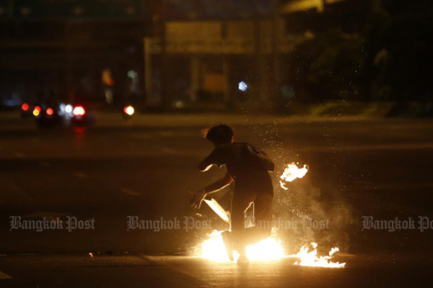 An anti-goverment protester lights a fire during a clash with riot police in Din Daeng area on Tuesday. (Photo: Wichan Charoenkiatpakul) An anti-goverment protester lights a fire during a clash with riot police in Din Daeng area on Tuesday. (Photo: Wichan Charoenkiatpakul)