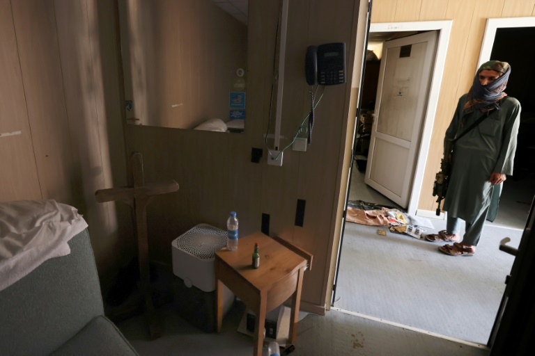 A Taliban fighter inspects a room with a cross and a bottle of Tabasco hot sauce at Kabul airport. A Taliban fighter inspects a room with a cross and a bottle of Tabasco hot sauce at Kabul airport.
