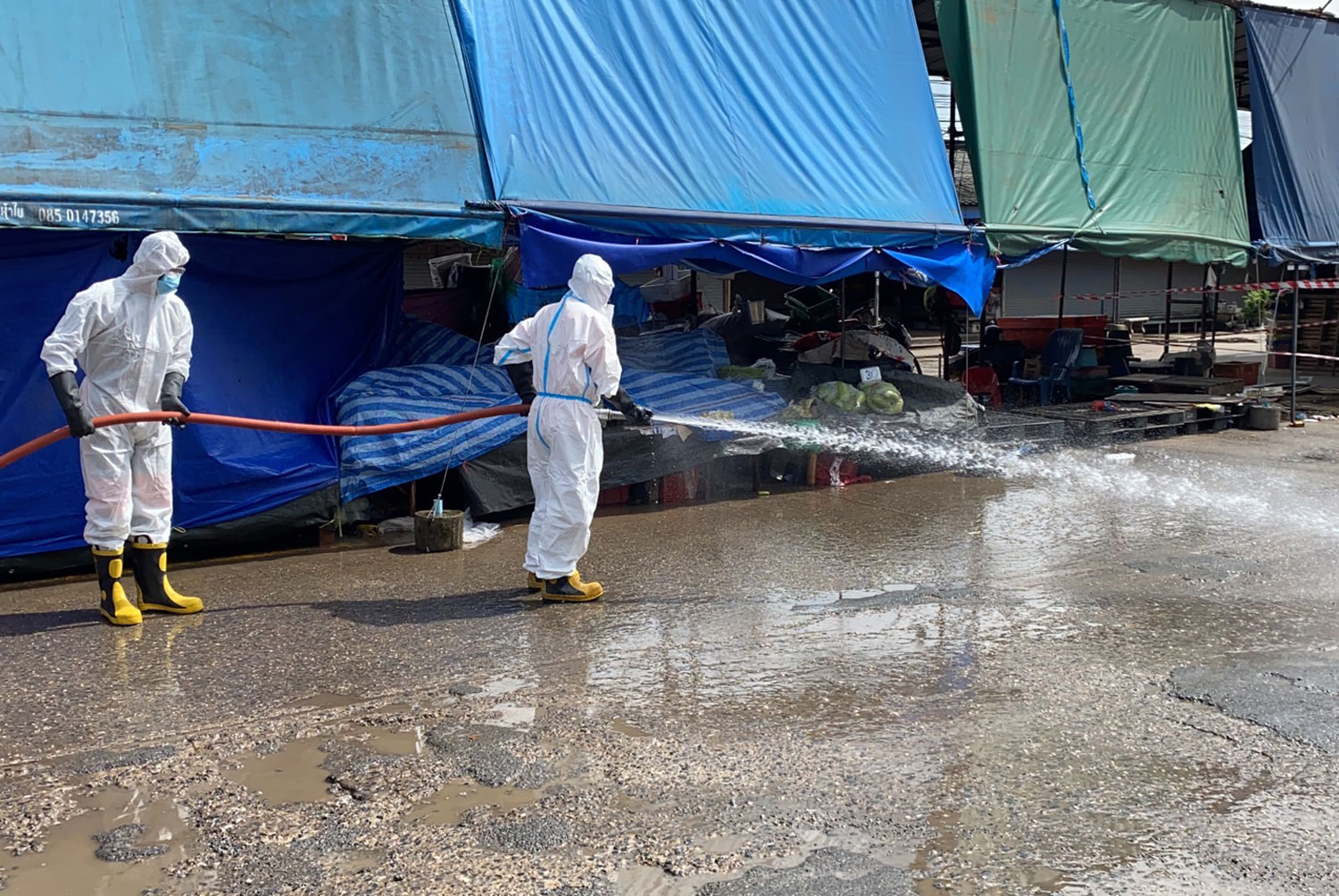 Two men clean an area around Talad Suranaree in Muang district of Nakhon Ratchasima province on Saturday. The largest wholesale market for fresh produce in the Northeast has been closed until Sept 25 due to the rising number of Covid-19 cases. (Photo: Prasit Tangprasert)