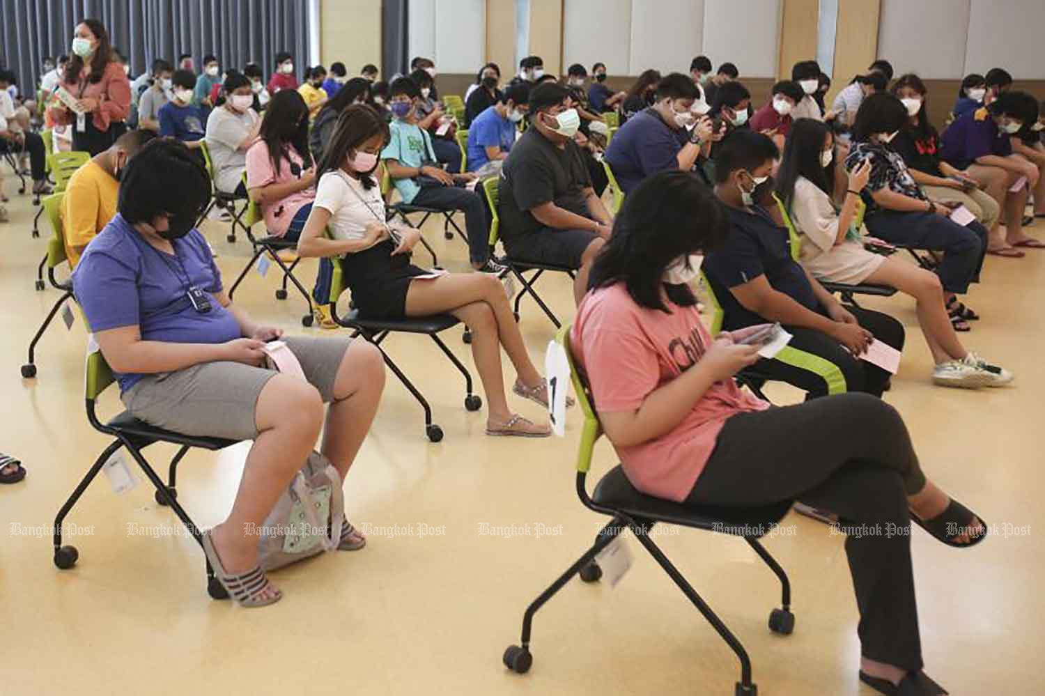 Youths wait for an injection of Pfizer vaccine at Vajira Hospital in Bangkok on Tuesday.