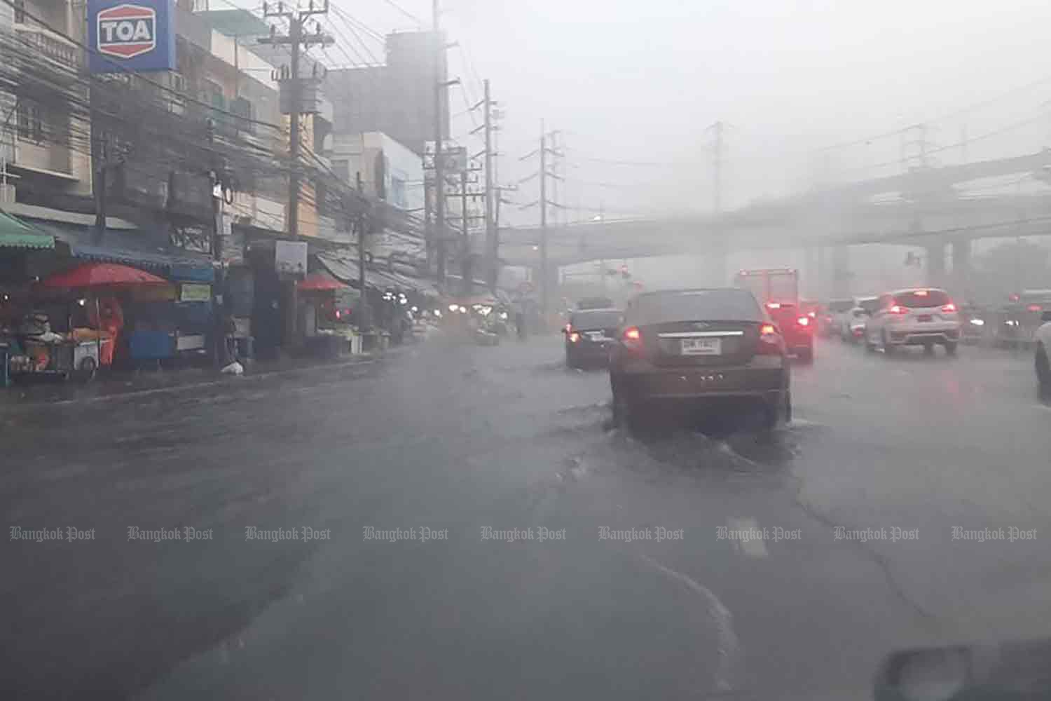 The road in Samut Prakan was inundated during a rainstorm on Monday, followed by two whirlwinds that struck housing estates in the area on Monday evening. (Photo: Sutthiwit Chayutworakan)