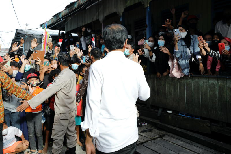 Locals gather and take pictures as they welcome Indonesian President Joko Widodo during a visit to inspect a door to door mass vaccination programme against the coronavirus disease at a residential area in Tarakan, North Kalimantan province, on Tuesday. (Reuters photo)