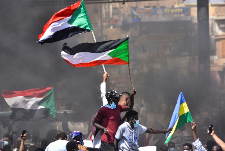 In this file picture taken on October 21, 2021, Sudanese demonstrators raise national flags as they take part in a protest in the city of Khartoum Bahri to demand the government's transition to civilian rule. In this file picture taken on October 21, 2021, Sudanese demonstrators raise national flags as they take part in a protest in the city of Khartoum Bahri to demand the government's transition to civilian rule.