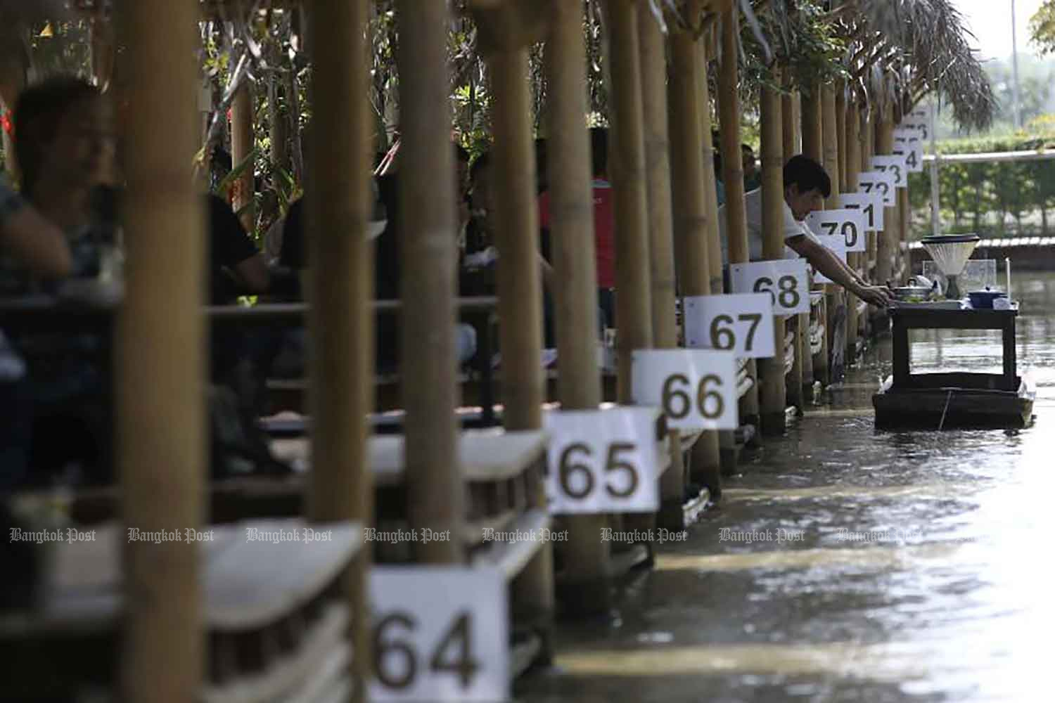 Food is served to customers from a small raft at Krua Sai Noi restaurant in Nonthaburi province on Tuesday. The popular service helps reduce physical contact between patrons and staff. (Photo: Pattarapong Chatpattarasill)