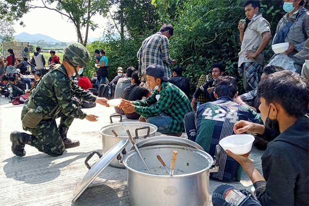 Soldiers offer food for illegal migrants from Myanmar after they were captured in Sai Yok district of Kanchanaburi on Sunday. (Photo: Piyarat Chongcharoen)