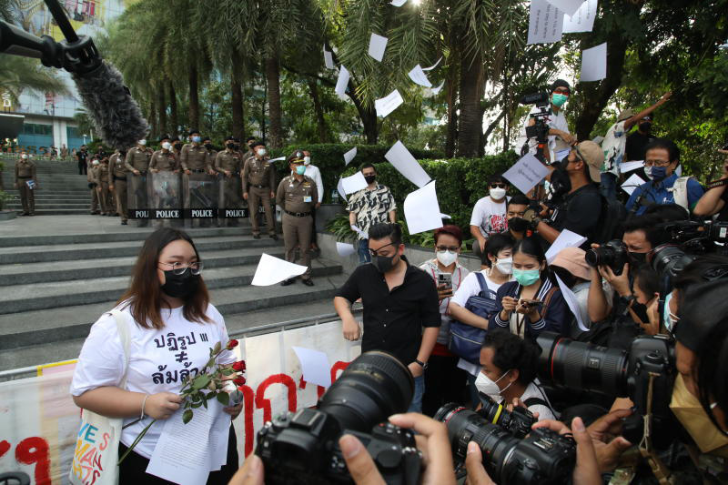 Activist Panusaya "Rung" Sithijirawattanakul talks to supporters outside the Constitutional Court after the ruling as they throw paper calling for the end of the lese majeste law into the air on Wednesday. (Photo: Arnun Chonmahatrakool)