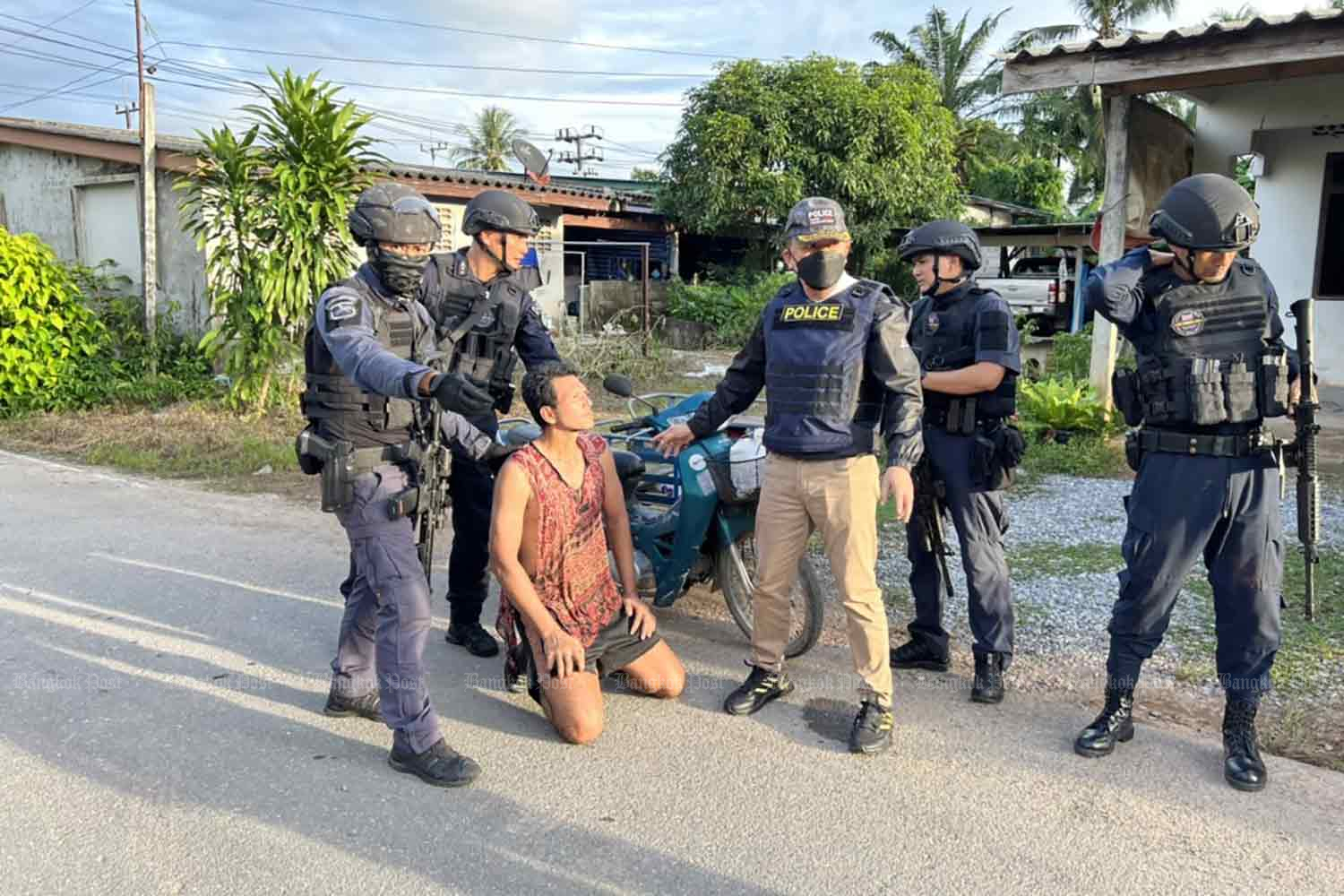 Surapong Klabkaew, kneeling, is arrested outside a house in Muang district, Satun, on Tuesday for attempted murder in Songkhla's Rattaphum district on Sunday. (Photo: Assawin Pakkawan)