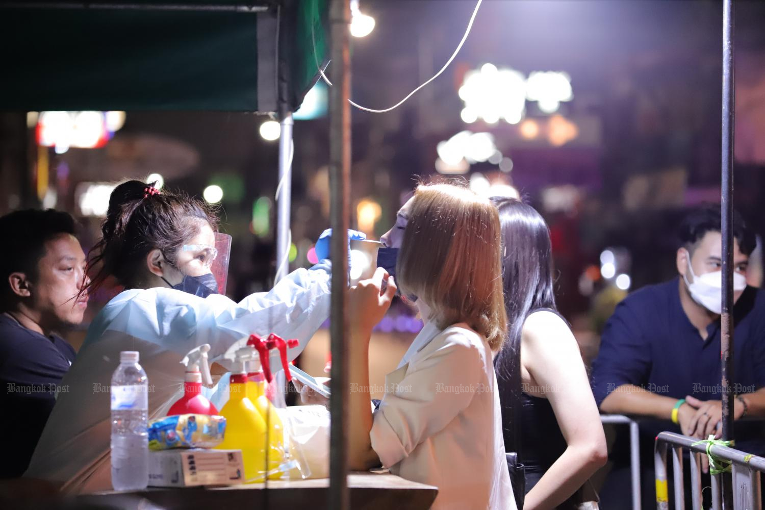 A health official performs an ATK test for a visitor at Khao San Road, following the detection of the first case of the Omicron variant in the country. (Photo by Pornprom Satrabhaya)