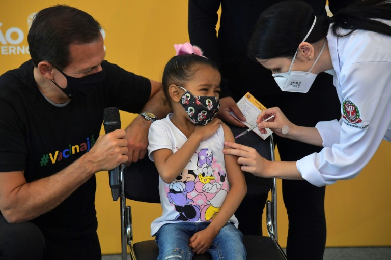 A child receives a Covid-19 vaccine in Brazil's Sao Paulo with local governor Joao Doria (L) looking on A child receives a Covid-19 vaccine in Brazil's Sao Paulo with local governor Joao Doria (L) looking on