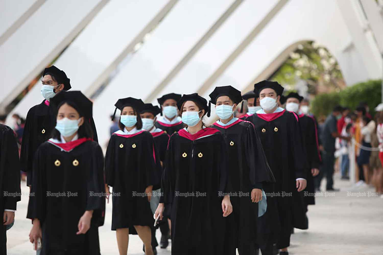 Rangsit University students attend their graduation ceremony on Sunday. The university had allowed fully vaccinated students to take their final exams if they could show a negative result from a rapid antigen test taken no more than 24 hours before entering the campus. (Photo: Varuth Hirunyatheb)