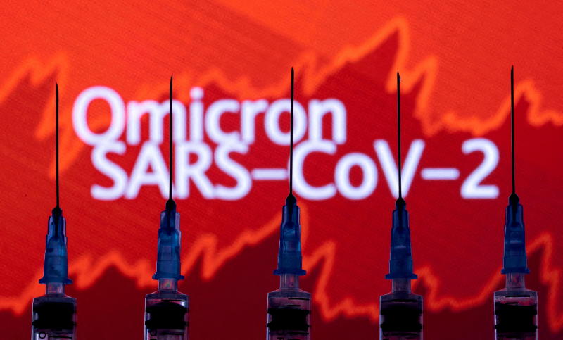 Syringes with needles are seen in front of a displayed stock graph and words Syringes with needles are seen in front of a displayed stock graph and words
