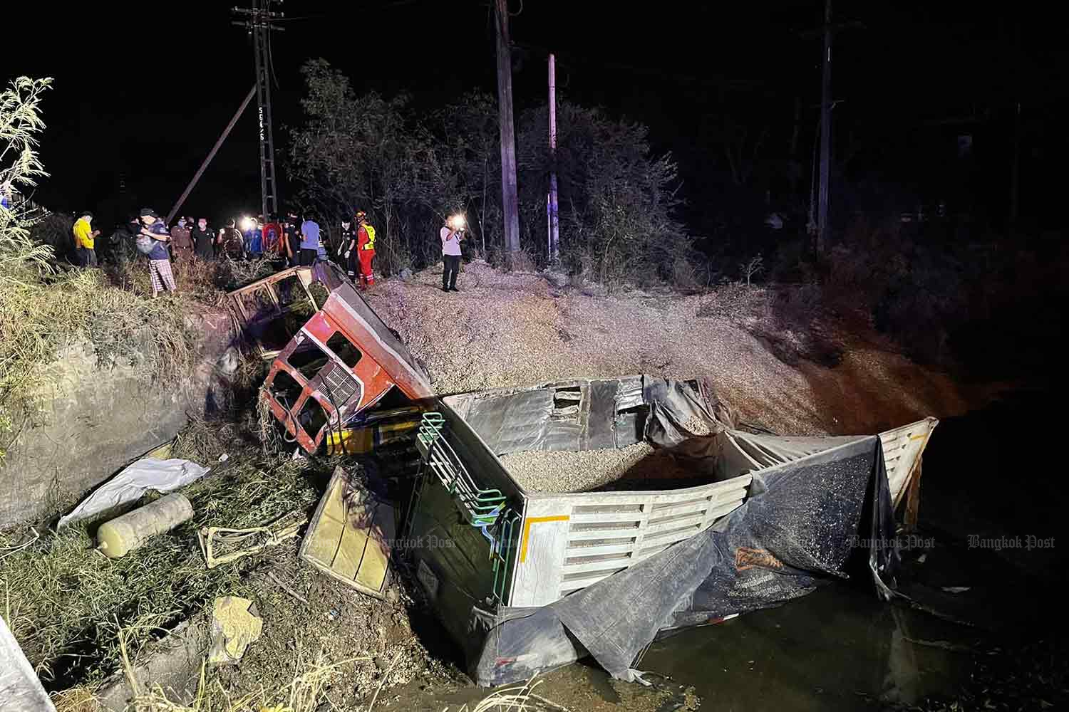 The wrecked truck trailer and its cassava chip cargo, hurled into the trackside canal when hit by a train at a railway crossing in Muang district, Udon Thani, on Monday night. The train driver and engineer were killed. (Photo: Rescuemetha28 Foundation)