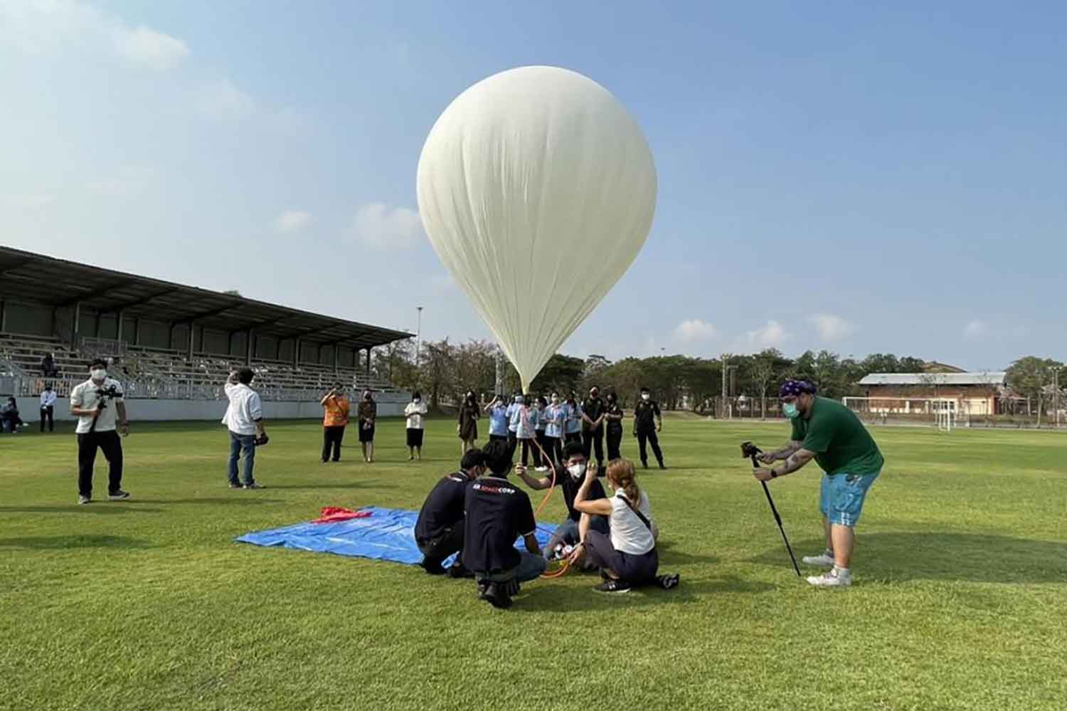 A research team inflates a balloon carrying a dish of rice topped with stir-fried pork with basil leaves and a fried egg. GISTDA photo