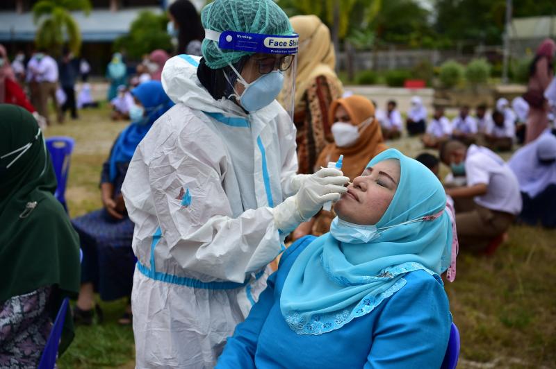 Public health officials conduct testing on teachers and students to prevent any infection with Covid-19 virus on the first day of school after being closed for a year due to the pandemic in Narathiwat on Friday. (AFP photo)