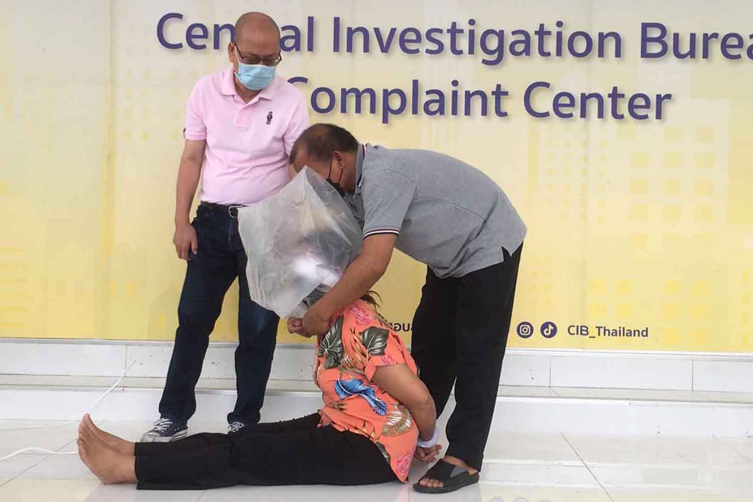 Mon Panthasaen, on the floor, demonstrates how she was tortured by police using a plastic bag nearly 15 years ago, when accused of having drugs in possession in Pathum Thani's Thanyaburi district, at the Central Investigation Bureau on Monday. (Photo supplied)