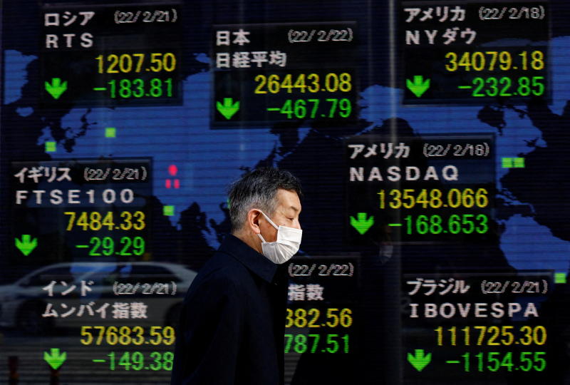 FILE PHOTO: A man walks past an electronic board displaying Japan's Nikkei index and various countries' stock market index prices outside a brokerage in Tokyo, Japan, Feb 22, 2022. (Reuters)